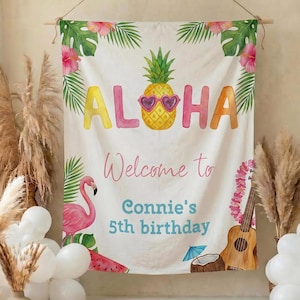 May include: A white fabric banner with the word "Aloha" in colorful letters, a pineapple wearing sunglasses, and tropical illustrations. The banner says "Welcome to Connie's 5th birthday". Decorative pampas grass and balloons are in the foreground.