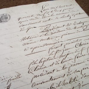 May include: An antique document with handwritten script in black ink on aged paper. The document features a circular stamp and appears to be a legal or historical record. The paper has a blue binding.