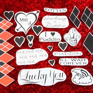 May include: A set of 15 temporary tattoos featuring various designs inspired by the character Harley Quinn. The tattoos include hearts, diamonds, text, and a jester's face. The text includes phrases like "Harley + Puddin", "I love Puddin", "Puddin", "Ill wait forever", "Lucky You", and "HA HA HA".