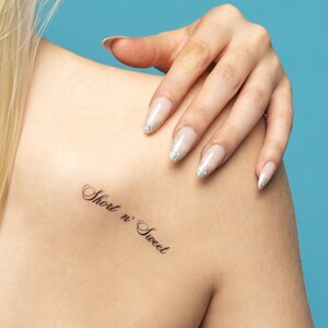 May include: A close-up of a person's shoulder with a small tattoo that reads "Short n' Sweet".