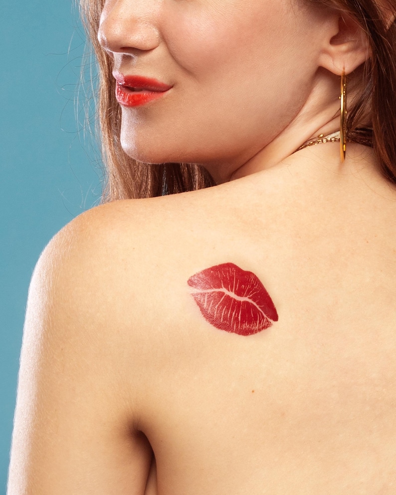 May include: A close-up of a woman's back with a red lipstick kiss mark on her shoulder.
