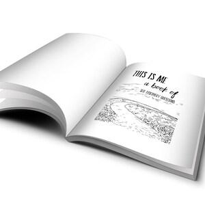 May include: An open book with a black and white illustration of a winding road. The text on the page reads "This is me a book of self discovery questions".