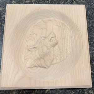 May include: A wooden plaque with a carved image of a wolf howling at the moon. The wolf is in the center of the plaque and is surrounded by a circular border.