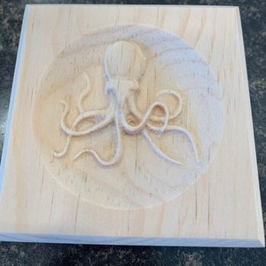 May include: A wooden plaque with a carved octopus design. The octopus is in a circle in the center of the plaque.