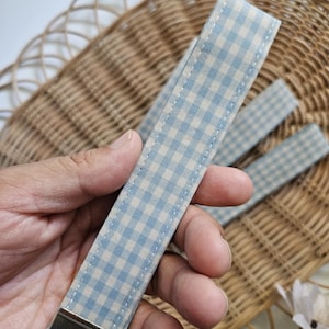 May include: A light blue and white gingham keychain with a silver key ring.