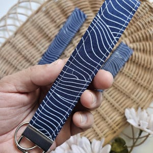 May include: A blue and white patterned fabric key chain with a silver key ring.