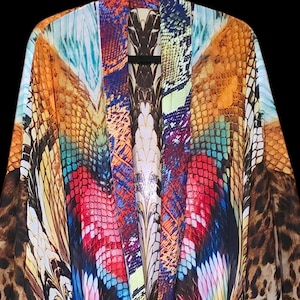 Könnte beinhalten: Ein farbenfrohes, fließendes Kleidungsstück mit einem lebendigen, abstrakten Design. Das Kleidungsstück weist eine Mischung aus Mustern auf, darunter Leopardenmuster und ein zentrales Design mit Blau-, Rot-, Gelb- und Orangetönen. Der Hintergrund ist schwarz.