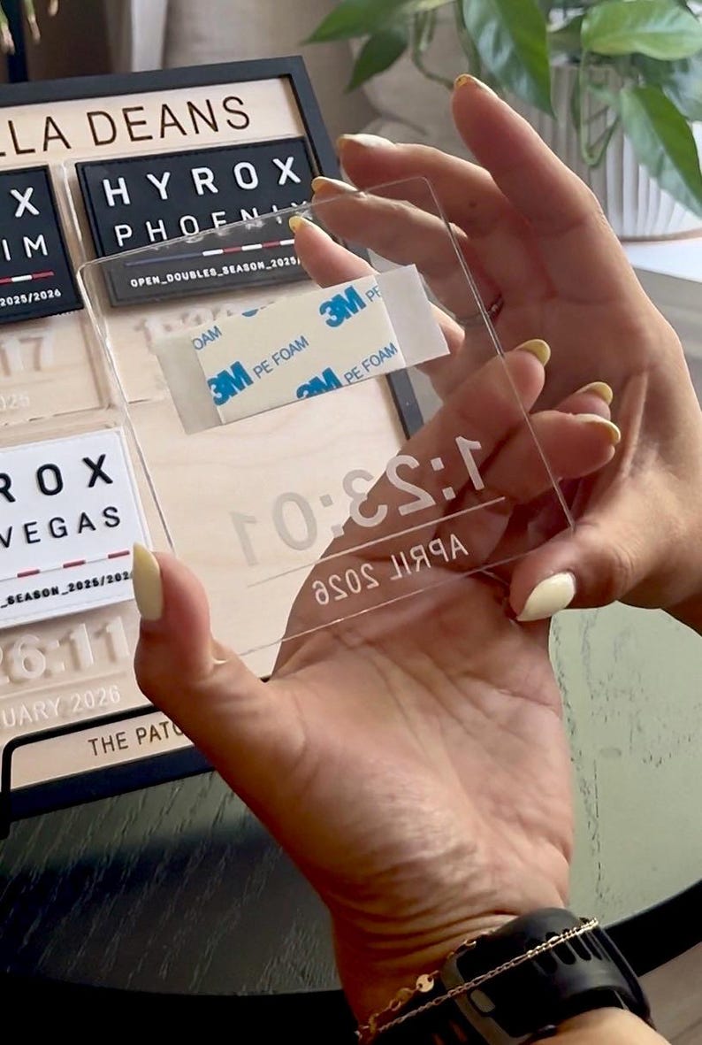 May include: A clear acrylic rectangle with the text "April Rose" and "1:53:0" printed on it. The rectangle has 3M PE foam tape on the back. The rectangle is being held in front of a black and white sign.