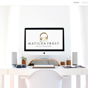 May include: A white desk with a white chair, a computer monitor, a keyboard, a mouse, and two speakers. The computer monitor displays a logo for Matilda Frost Virtual Assistant, featuring a gold headphone icon with a heart inside.