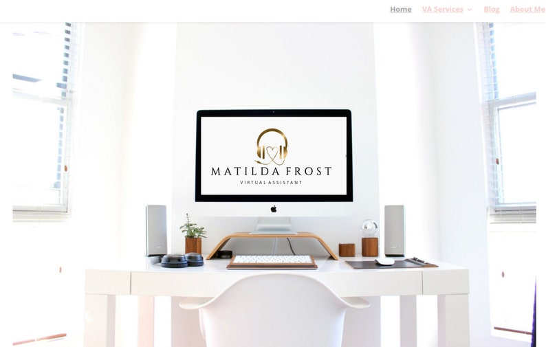 May include: A white desk with a white chair, a computer monitor, a keyboard, a mouse, and two speakers. The computer monitor displays a logo for Matilda Frost Virtual Assistant, featuring a gold headphone icon with a heart inside.