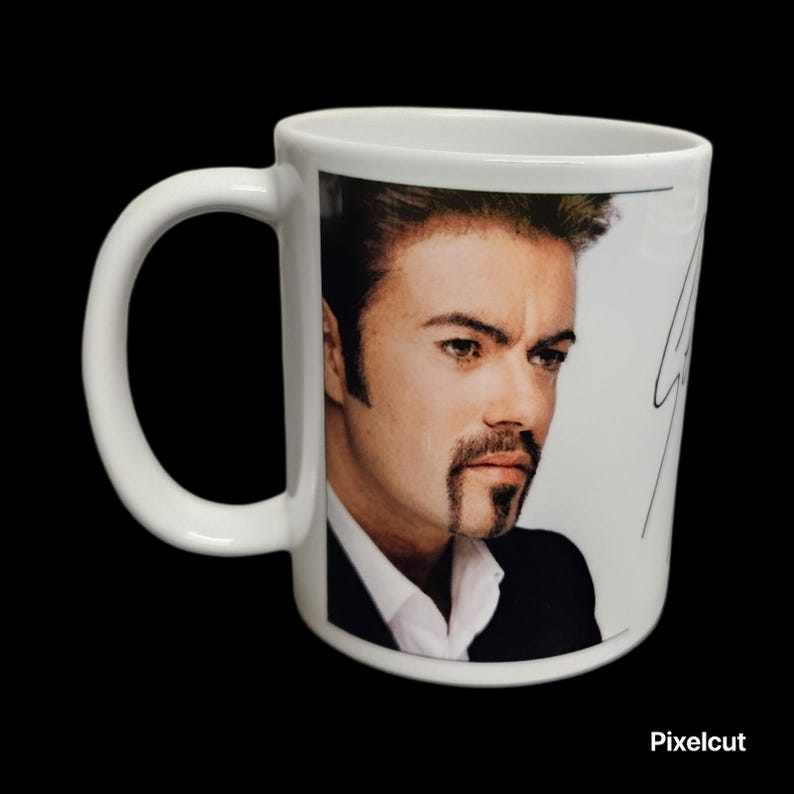 May include: White ceramic mug featuring a portrait of a man with dark hair and a mustache. The mug has a white handle and a black background. The mug has a signature on the side.