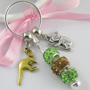 May include: A silver key chain with a gold kangaroo charm, a silver koala charm, and green and brown beaded charms.