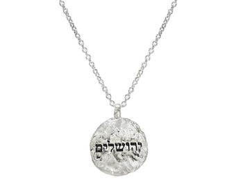 Könnte beinhalten: Silberkette mit einem runden Anhänger mit den hebräischen Worten "Derech Hashem" (Der Weg des Herrn).