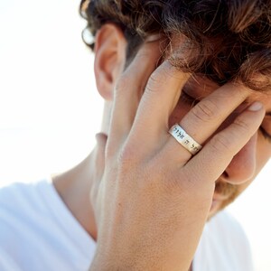K&ouml;nnte beinhalten: Nahaufnahme einer Hand, die einen silbernen Ring mit hebr&auml;ischer Beschriftung tr&auml;gt. Der Ring befindet sich am Mittelfinger der rechten Hand.