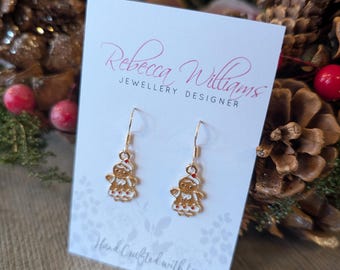 May include: Gold-colored dangle earrings featuring gingerbread man charms. The earrings are displayed on a white card with the text "Rebecca Williams JEWELLERY DESIGNER" and "Hand Crafted with Love."
