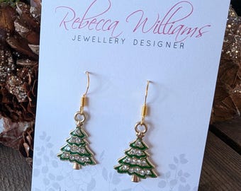 May include: Gold-tone Christmas tree earrings with green enamel and clear crystal accents. The earrings are displayed on a card with the text "Rebecca Williams Jewellery Designer" and "Hand Crafted with Love".