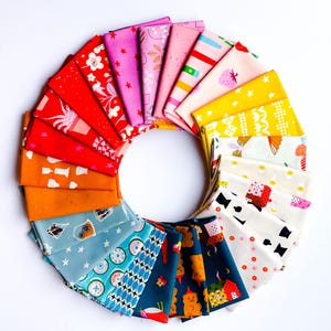 May include: A circular arrangement of folded fabric squares featuring a diverse spectrum of colors including red, orange, blue, yellow, pink, and white. The textiles display various patterns such as stars, flowers, geometric shapes, and animals.