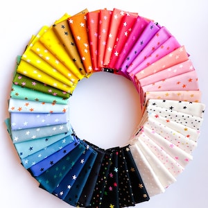 May include: A circular arrangement of folded fabric swatches featuring a repeating star pattern. The collection displays a full spectrum of colors including yellow, orange, red, pink, light blue, dark blue, black, and white with various star colors.