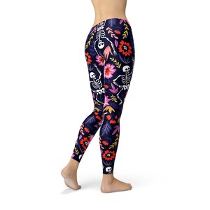 May include: Black leggings with a floral and skeleton pattern. The flowers are pink, red, and yellow. The skeletons are white.
