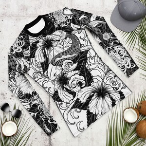 May include: Black and white long-sleeved shirt with a graphic print of koi fish and flowers. The design is intricate and detailed, with a traditional Japanese style.