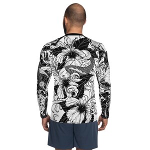 May include: Black and white long-sleeve shirt with a graphic print of koi fish and hibiscus flowers.