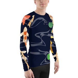 May include: A long-sleeved navy blue shirt featuring a koi fish design. The shirt has a crew neck and a pattern of orange, white, and black koi fish swimming in a dark blue pond with lily pads.