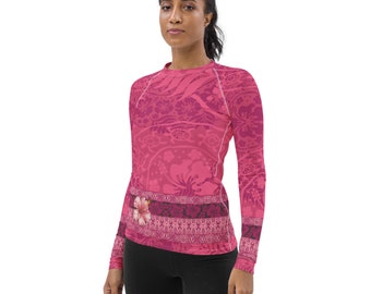 May include: A pink long-sleeved shirt with a floral pattern and a hibiscus flower on the chest. The shirt has a fitted silhouette and a crew neckline.