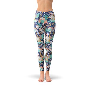 May include: Navy blue leggings featuring a repeating pattern of sloths and tropical leaves in teal, coral, and gold. The leggings are high-waisted and form-fitting, suitable for yoga or everyday wear.