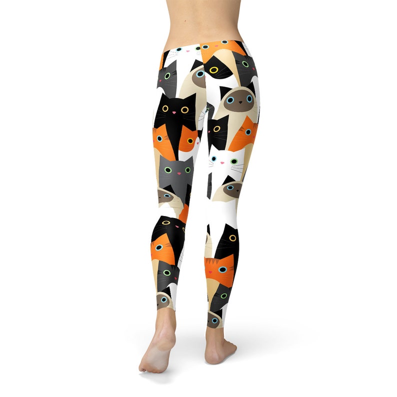 May include: Black, white, and orange leggings with a repeating pattern of cats. The cats are all different colors and have different expressions.