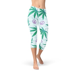 May include: White capri leggings with a green marijuana leaf and purple peace sign pattern.