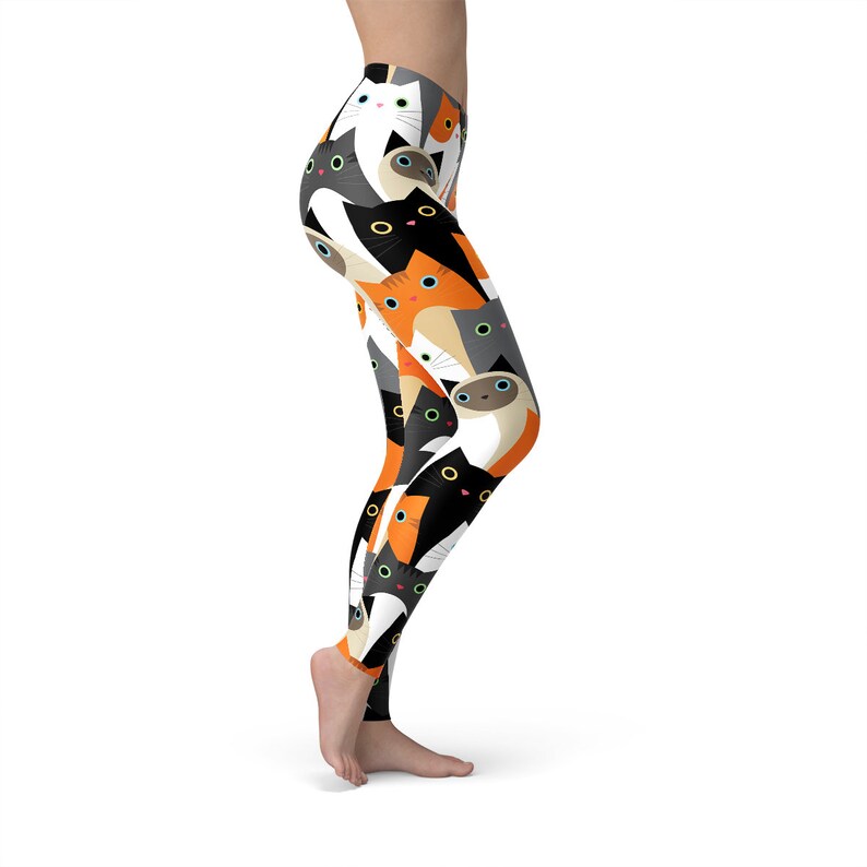 May include: Black, white, orange, and gray leggings with a repeating pattern of cartoon cats. The cats have different colored eyes and are looking in different directions.