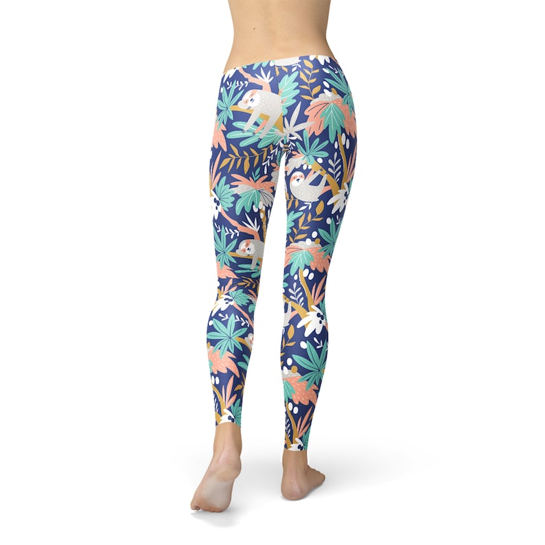 May include: Navy leggings featuring a repeating pattern of sloths, tropical plants, and flowers in white, coral, and teal. The leggings are form-fitting and made of a soft, stretchy material.