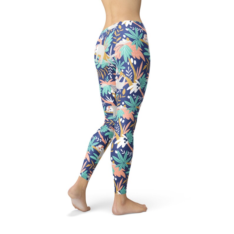 May include: Navy blue leggings with a colourful tropical pattern. The design features sloths, palm trees, and other foliage in shades of white, teal, coral, and yellow. The leggings are form-fitting and made of a stretchy material.