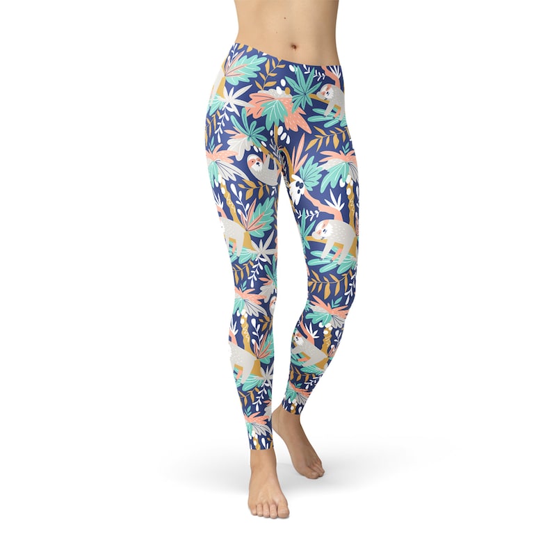 May include: Navy blue leggings featuring a repeating pattern of sloths, tropical leaves, and flowers in white, teal, coral, and gold. The leggings are form-fitting and made of a stretchy material.