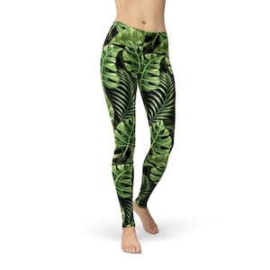 Peut inclure: Leggings noirs avec un imprimé de feuilles tropicales vertes. Les feuilles sont de formes et de tailles variées et sont disposées de manière aléatoire.