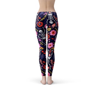 May include: Black leggings with a floral and skeleton pattern. The flowers are pink, red, orange, and yellow. The skeletons are white.