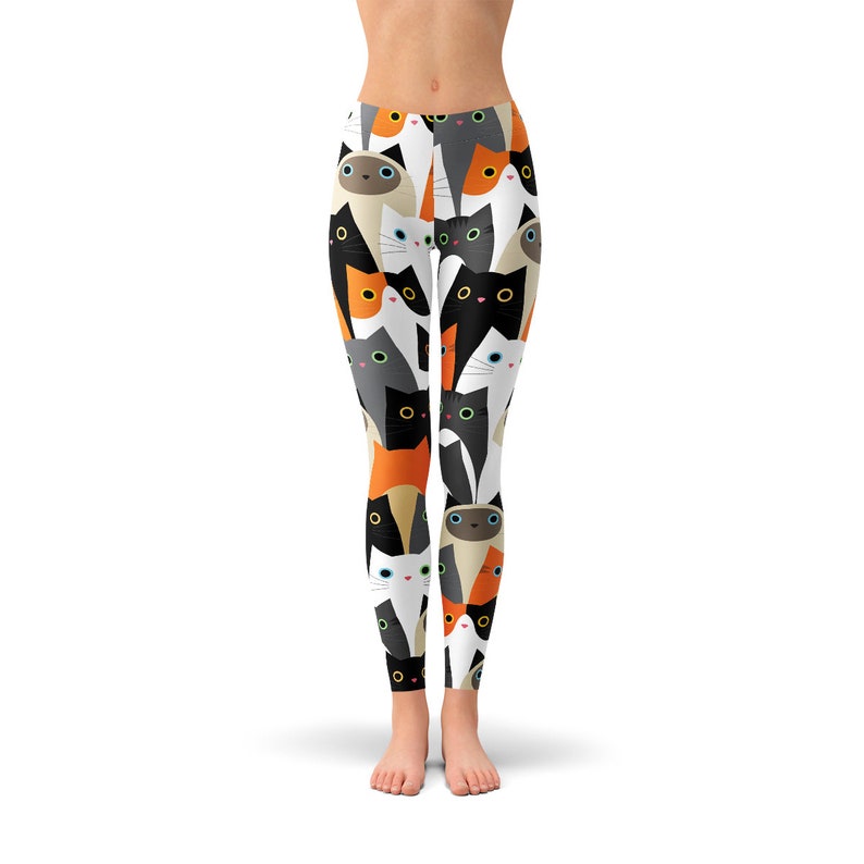 May include: White leggings with a repeating pattern of colorful cartoon cats. The cats are in various poses and have different colored fur and eyes.