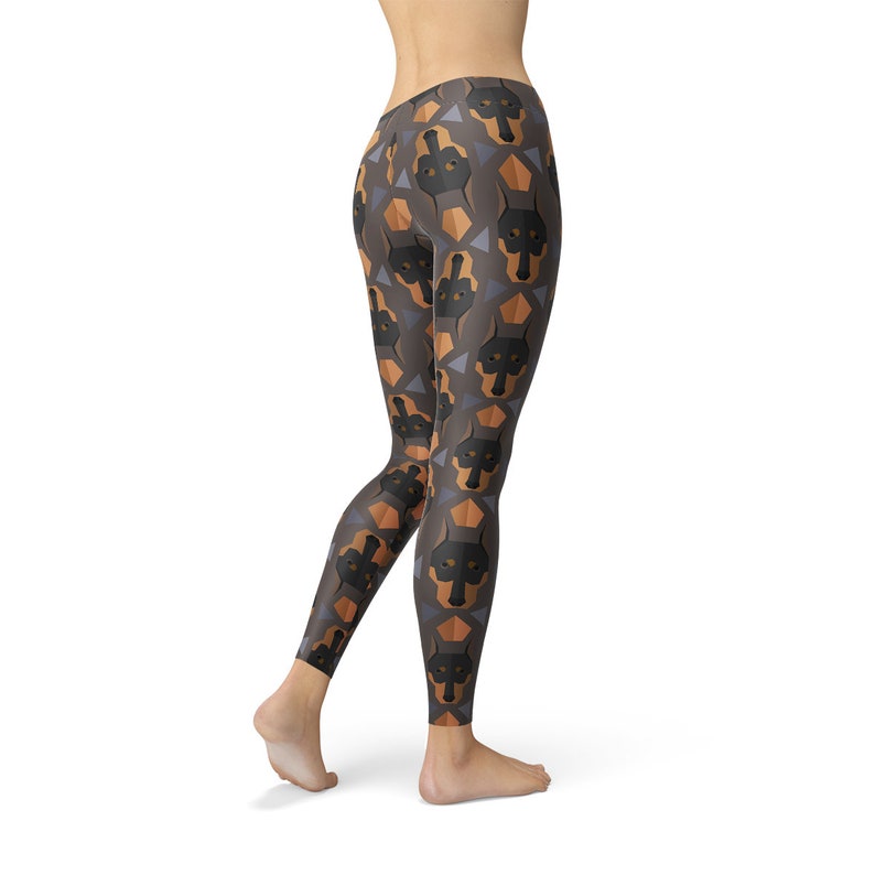 May include: Black leggings with a geometric pattern of brown and black Doberman Pinscher dog faces on a gray background.