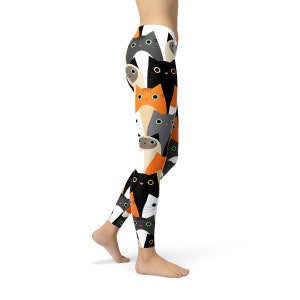 May include: White leggings with a colorful pattern of cats. The cats are in various colors, including black, orange, gray, and white. The cats are all looking at the viewer.