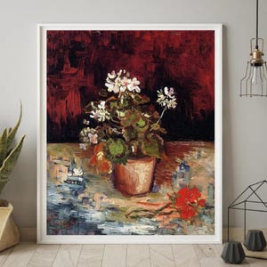 May include: A framed art print of a still life painting featuring a potted geranium with white and pink flowers. The painting has a dark red background and a light blue and tan foreground. A red flower lies on the table.