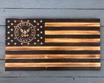 May include: A wooden American flag with a distressed finish. The flag features the United States Navy seal in the upper left corner.