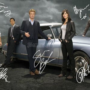 Puede incluir: Un grupo de cinco personas se encuentra frente a un coche plateado. Las personas visten ropa informal. El coche tiene una firma en el lateral que dice "The Mentalist".