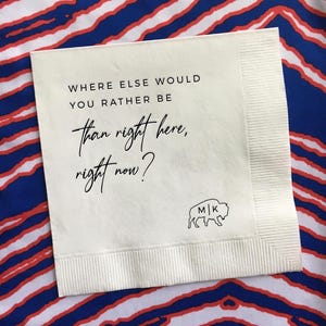 May include: White paper napkin with the text "Where else would you rather be than right here, right now?" and a black buffalo silhouette with the initials "M|K" in the center.