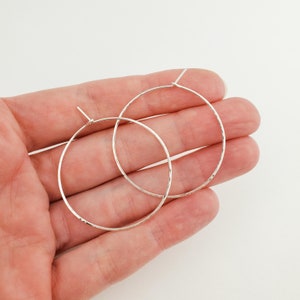 May include: A pair of silver hoop earrings with a hammered texture.