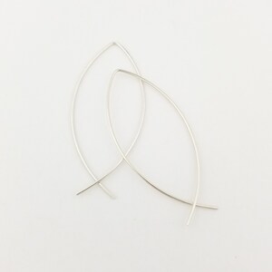 May include: A pair of silver hoop earrings with a unique, curved, teardrop shape.