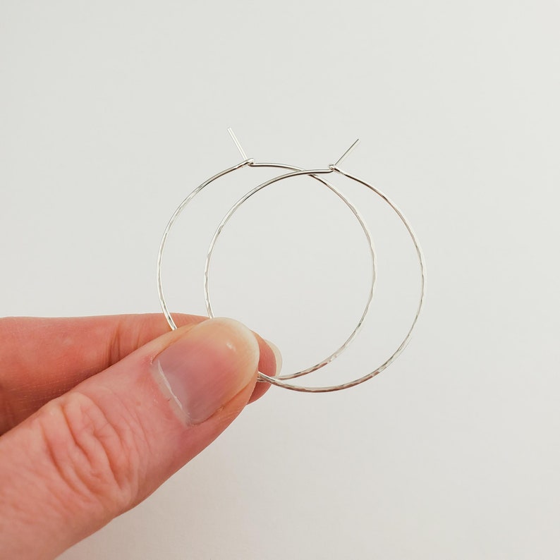 May include: A pair of silver hoop earrings with a hammered texture.