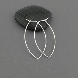 May include: A pair of silver oval hoop earrings. The earrings are simple and elegant, and they would be a great addition to any jewelry collection.