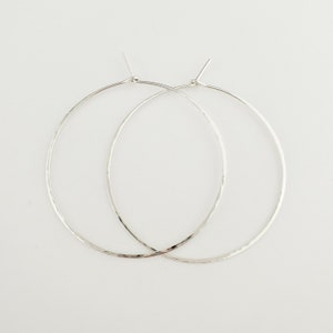 May include: A pair of silver hoop earrings with a hammered texture.