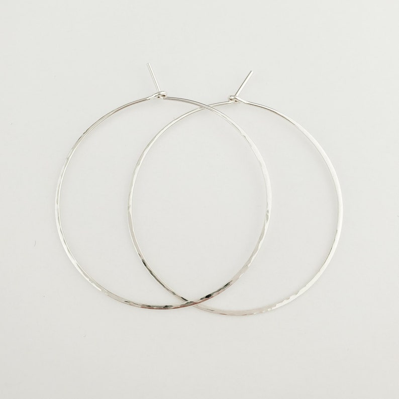May include: A pair of silver hoop earrings with a hammered texture.