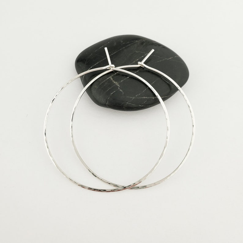 May include: A pair of silver hammered hoop earrings. The earrings are simple and elegant, and they would make a great gift for any occasion.